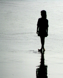 silhouette of a girl on a beach with shadow reflection in the wet sand